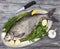 A large live bream river fish fish lying on a on on an iron tray with a knife and slices of lemon and with salt dill