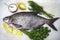 A large live bream river fish fish lying on a paper background with and slices of lemon and with salt dill