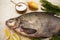 A large live bream river fish fish lying on a paper background with and slices of lemon and with salt dill