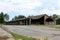 Large long hangar building with destroyed support walls and unusual bent roof surrounded with paved area at abandoned military