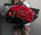 A large lush bouquet of red garden roses and buds in black wrapping paper, a stylish