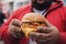 Large man holds small burger in his hand, close up shot