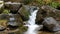 Large massive black stones on which water flows from mountain transparent stream