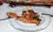 Large Mediterranean prawn with mamuskami , green sauce and lemon on a white plate