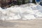 A large melting pile of snow on the dried asphalt in the spring. It`s the snow that`s being taken out of the rink