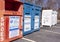 Large metal clothing and shoes donation bins lined side by side on a parking lot