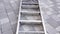 Large metal ladder lies on grey paved sidewalk closeup