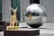 A large metal mirror ball among dark gray office buildings, a modern work of art. Recreation area for office workers. wooden