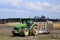 A large modern John Deere tractor tows a cultivator in a field