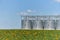 Large modern wheat elevator, granary and field with a blooming sunflower