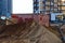 A large mountain of sand lies on a construction site in the city center. sand lies against the backdrop of large orange dumpsters