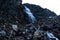 Large mountain waterfall in the mountains on the dark wet rocks, evening landscape long exposure