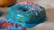 Large multi-colored fresh fried donuts in a row on a table. A beautiful donut with blue icing is sprinkled with a