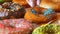 Large multi-colored fresh fried donuts in a row on a table. A beautiful donut with orange icing is sprinkled with a