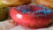 Large multi-colored fresh fried donuts in a row on a table. A beautiful donut with pink icing is sprinkled with a