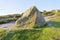 Large multicoloured Derbyshire gritstone rock in the early morning sunlight