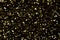A large number of defocused shiny gold sequins on a black background.Texture or background