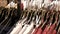 A large number of women`s clothing of different colors hangs on hangers and lies on the shelves in a clothing store of