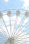 Large observation wheel against blue cloudy sky, low angle view