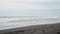 A large ocean beach with black volcanic sand.