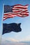 Large official Flag of US with smaller flag of Alaska state, Usa at cloudy sky background. United states of America patriotic