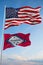 Large official Flag of US with smaller flag of Arkansas state, Usa at cloudy sky background. United states of America patriotic