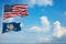 Large official Flag of US with smaller flag of Louisiana state, Usa at cloudy sky background. United states of America patriotic