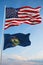 Large official Flag of US with smaller flag of Vermont state, Usa at cloudy sky background. United states of America patriotic