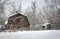 Large old brown wooden barn sitting behind a fence made of wood posts.