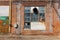 A large old dilapidated house of red and white bricks with a large dilapidated window and a multi-colored metal door. Old dirty