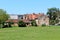 Large old red brick family houses next to elongated outdoor storage building with cracked facade and destroyed roof