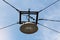 Large old street lamp within strong metal casing suspended with dark electrical wires in old part of town