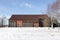 Large old wooden barn with rusting metal roof seen in rural area during an early winter sunny morning