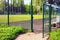 A large open metal door in a painted metal mesh fence, behind which you can see a green football field and benches with a white