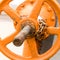 Large orange iron round valve on a long rusty bolt pressure adjustment flow industrial grunge style background