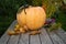 A large orange pumpkin lies on a wooden table. Nearby there is a candle on a pumpkin spider