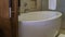 A large oval acrylic bathtub next to a beige tiled wall.