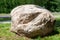 A large oval stone lies on the green grass