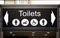 Large overhead black and white toilets sign with male, female, disabled and baby changing icons.