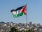 The large Palestinian flag (flag of Palestine) is waiving above the city