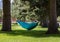 Large person reading book in hammock in park