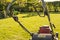 Large petrol powered lawn mower seen in a large, well maintained garden after being mowed