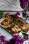 A large pie, cut into portions, stuffed with fruit and berries, among the branches of purple lilac blooming in spring