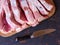 A large piece of raw pork meat chopped into pieces on a cutting board on an old rustic table black and stainless steel kitchen