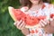 Large piece of red juicy watermelon. Green background. Girls han