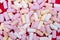 A large pile of multi-colored marshmallows scattered on a red background