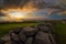 a large pile of rocks sits on the grass at sunset