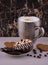 Large pimpled silver cup of coffee and cakes bisquits chocolate and coffee beans on the white reflective surface