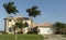 Large pink and yellow tropical house with circular driveway.