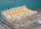 Large piped meringue pavlova cake, decorated with piped cream and lemon curd in a herringbone pattern.
